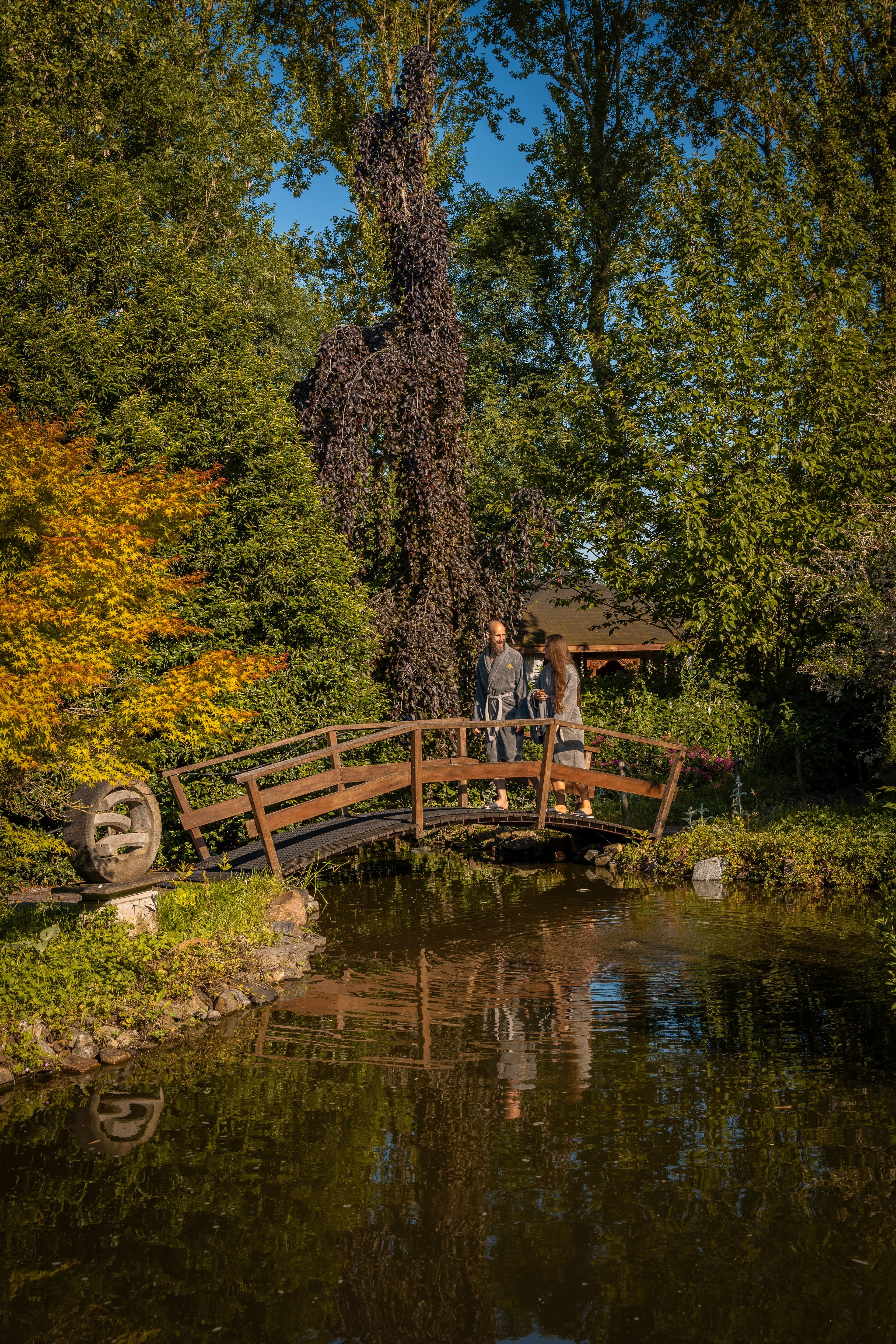 Houten brug over een vijver in de natuurlijke tuinen van Thermen Binnenmaas
