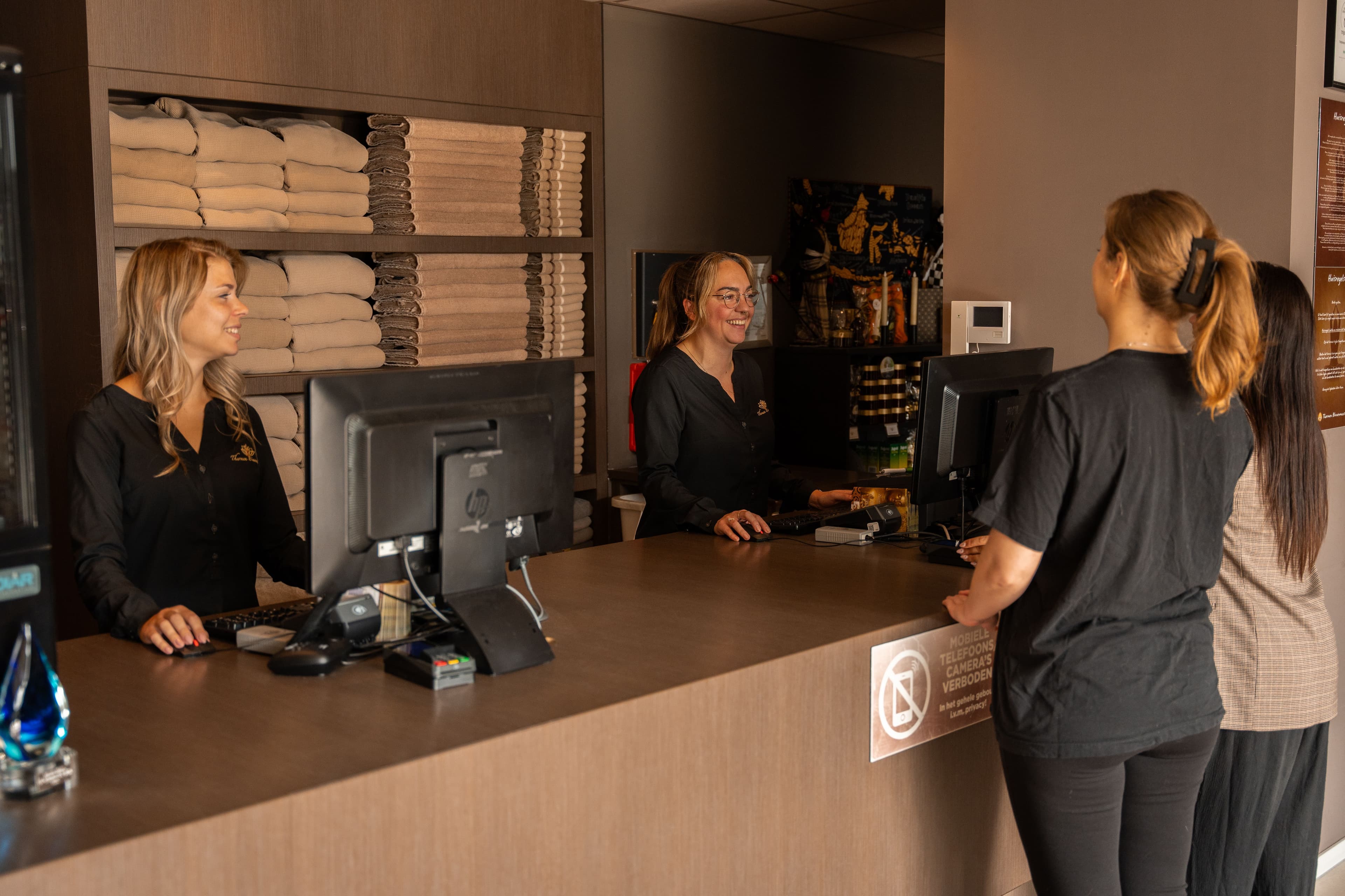 Receptiemedewerkers helpen gasten vriendelijk bij aankomst in het wellnesscentrum.