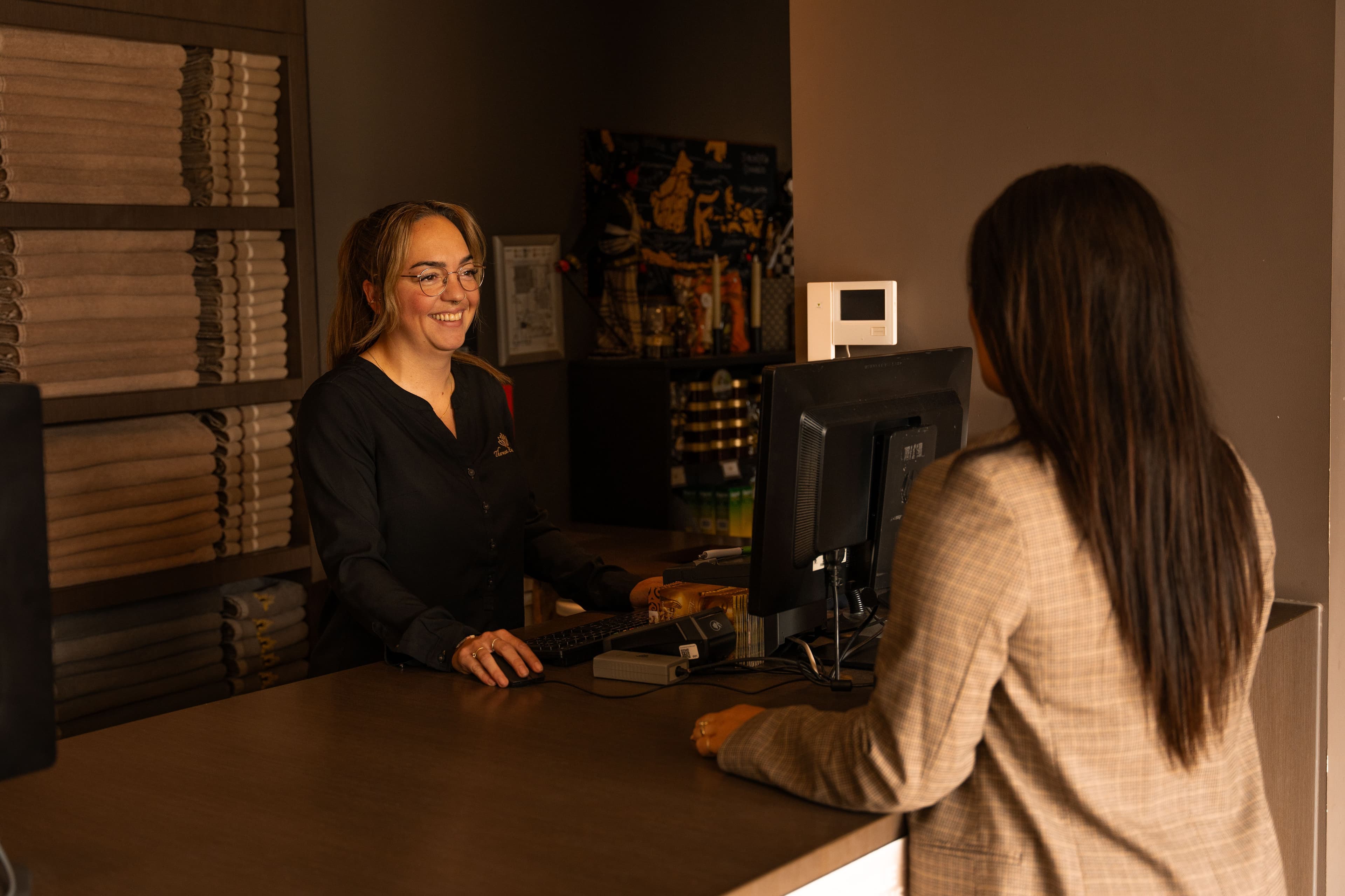 Receptiemedewerker helpt gast bij het inchecken in het wellnesscentrum