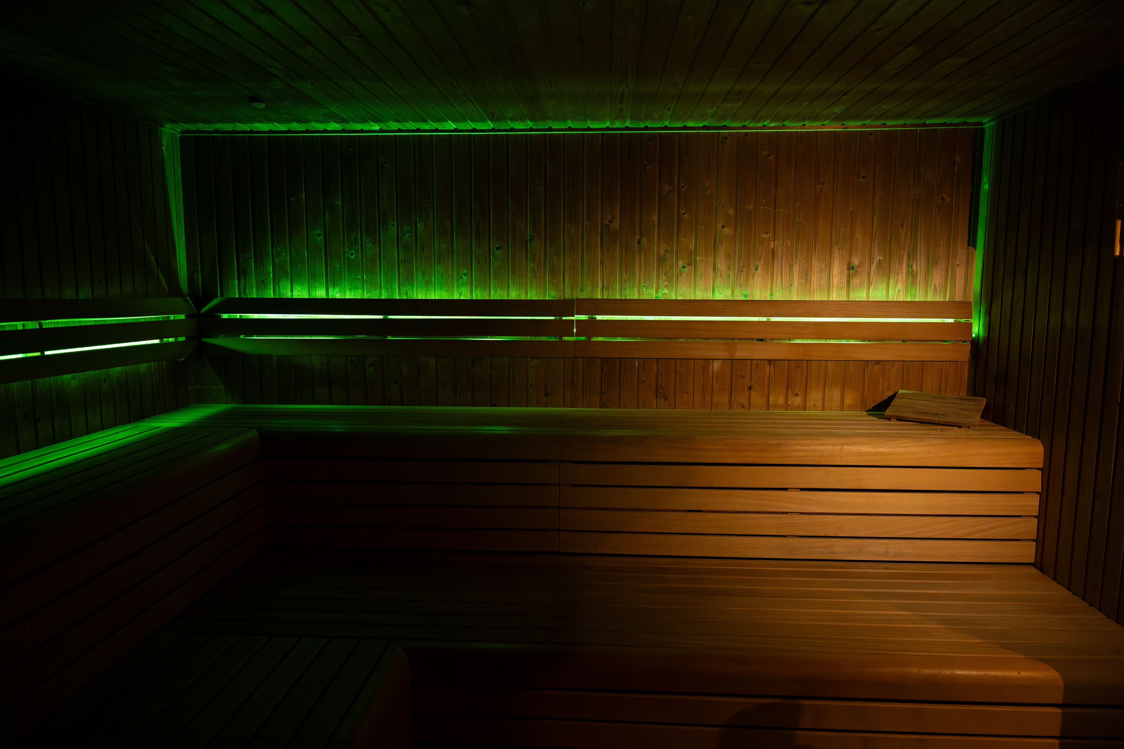 Sauna met groene sfeerverlichting en houten banken voor een unieke wellnesservaring
